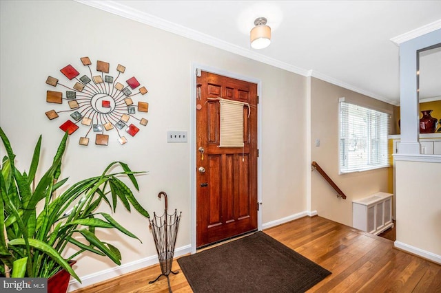 foyer with ornamental molding, visible vents, baseboards, and wood finished floors