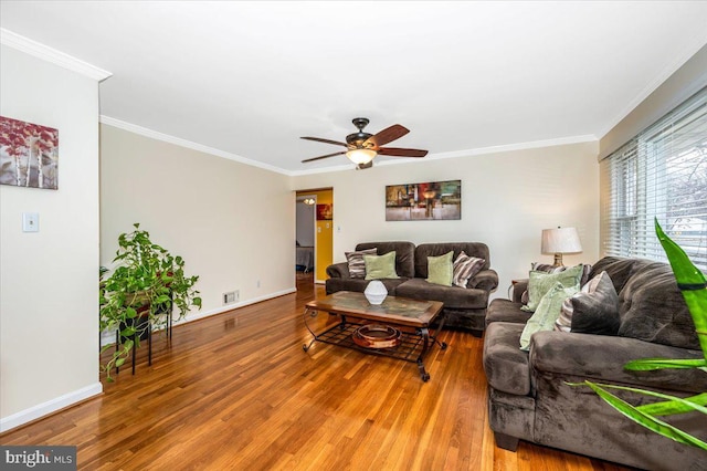 living area featuring baseboards, wood finished floors, and crown molding