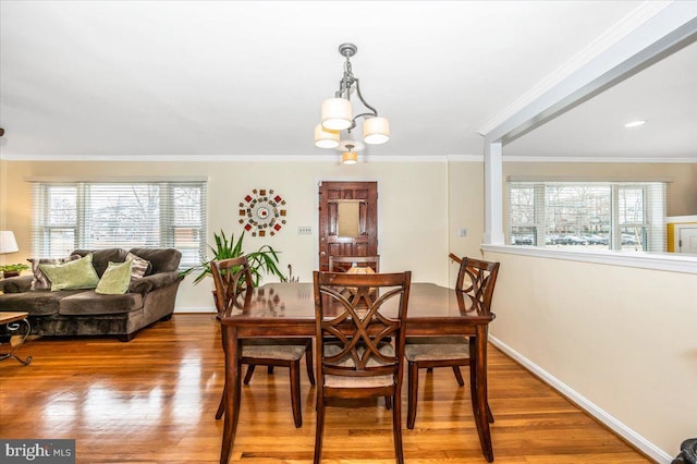 dining area with baseboards, ornamental molding, wood finished floors, and an inviting chandelier