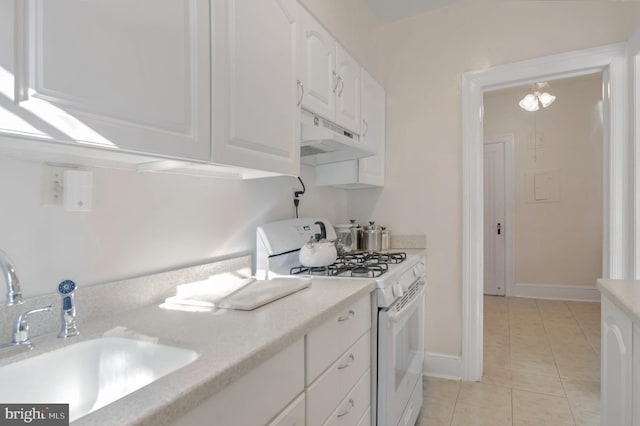 kitchen featuring white cabinetry, white gas stove, light tile patterned flooring, and sink