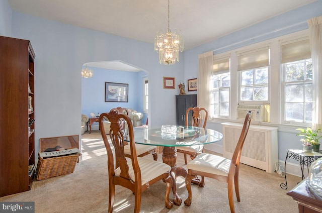 carpeted dining space featuring cooling unit, radiator heating unit, and a chandelier