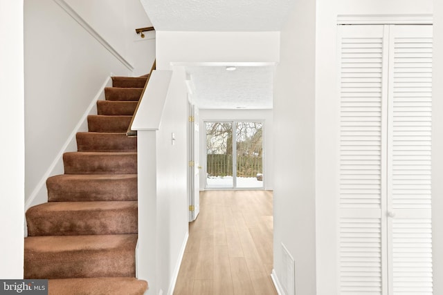 stairs with wood-type flooring and a textured ceiling