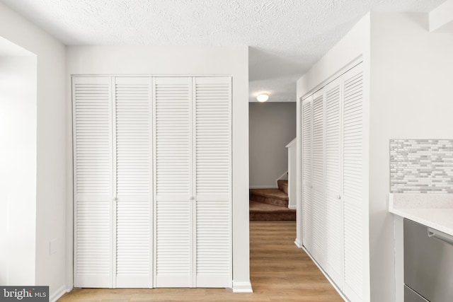 hall with light hardwood / wood-style floors and a textured ceiling