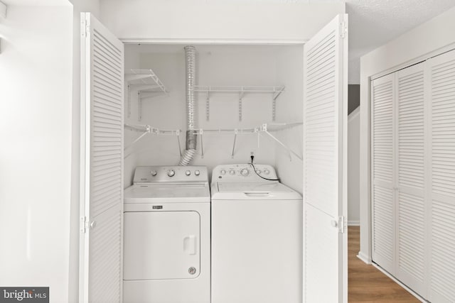 clothes washing area featuring hardwood / wood-style floors, washer and dryer, and a textured ceiling