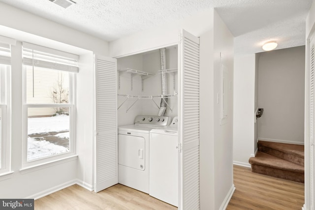 washroom featuring washing machine and dryer, a textured ceiling, and light hardwood / wood-style flooring