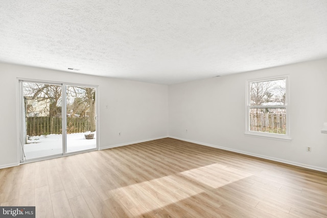 unfurnished room with plenty of natural light, light hardwood / wood-style floors, and a textured ceiling