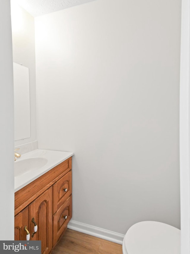 bathroom with a textured ceiling, vanity, hardwood / wood-style flooring, and toilet