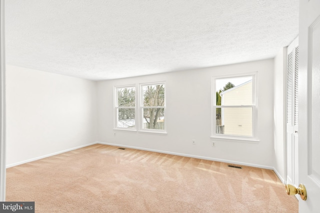 carpeted spare room with a textured ceiling