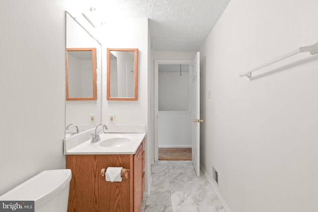 bathroom with vanity, a textured ceiling, and toilet