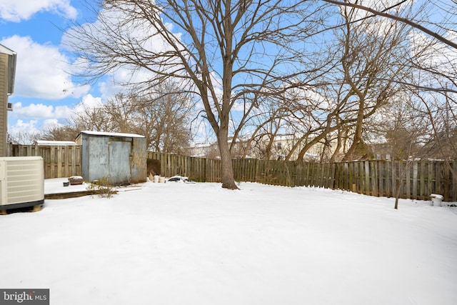 yard covered in snow featuring cooling unit and a shed