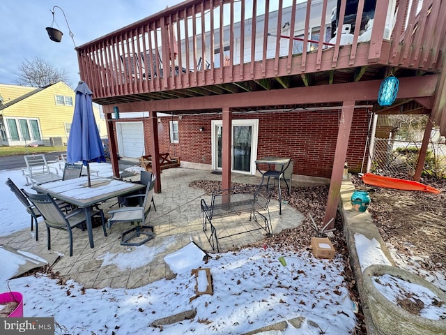 snow covered patio with a wooden deck