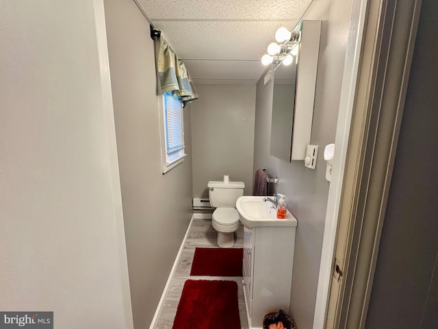 bathroom with baseboard heating, a paneled ceiling, hardwood / wood-style floors, toilet, and vanity