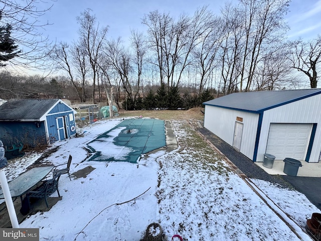 yard layered in snow featuring a covered pool and a storage shed