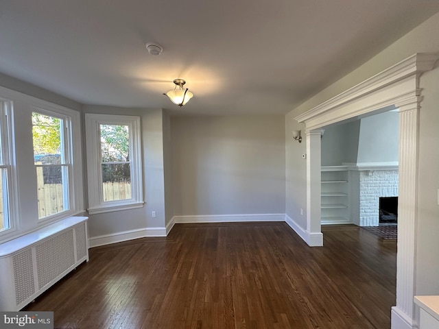 unfurnished room featuring a fireplace, radiator heating unit, and dark hardwood / wood-style flooring