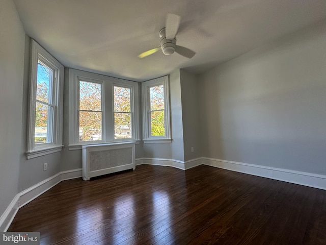 unfurnished room with radiator, ceiling fan, plenty of natural light, and dark hardwood / wood-style floors