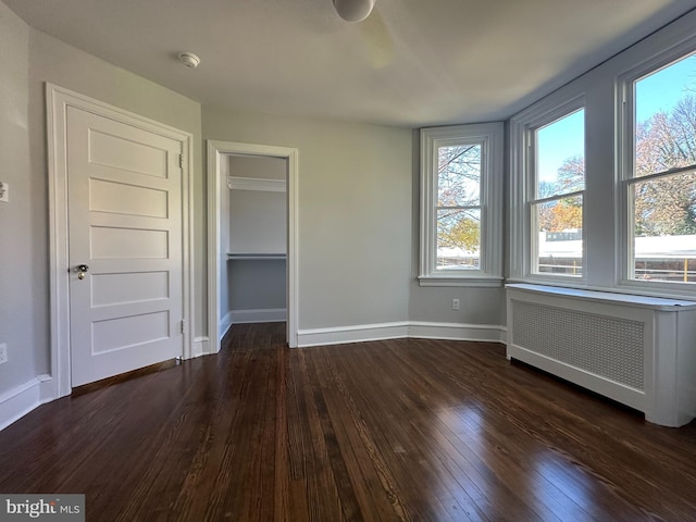 spare room with dark hardwood / wood-style floors and radiator heating unit