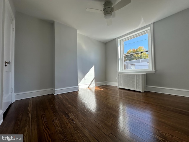 unfurnished room featuring radiator, ceiling fan, and dark wood-type flooring