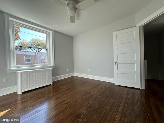 unfurnished room with ceiling fan, dark hardwood / wood-style flooring, and radiator