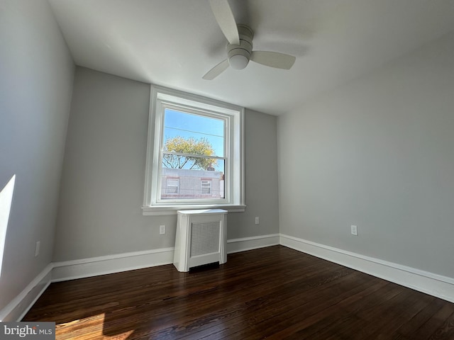 spare room featuring ceiling fan, radiator heating unit, and dark wood-type flooring