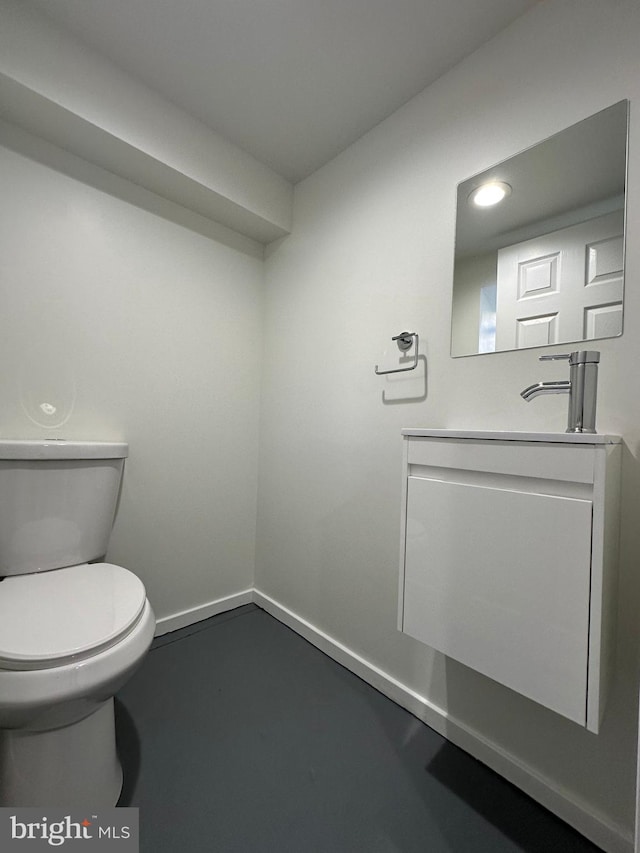 bathroom with concrete flooring, vanity, and toilet