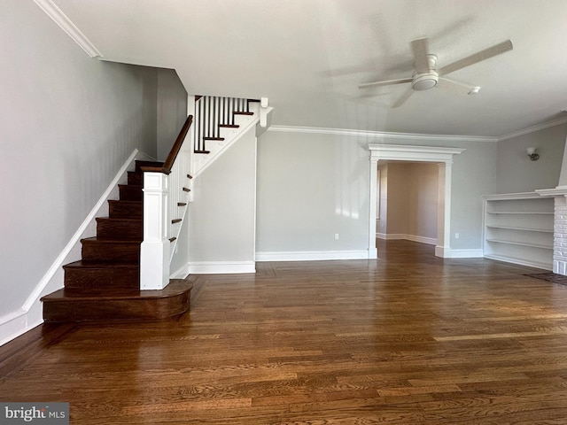 unfurnished living room with ceiling fan, a brick fireplace, dark hardwood / wood-style flooring, built in features, and ornamental molding