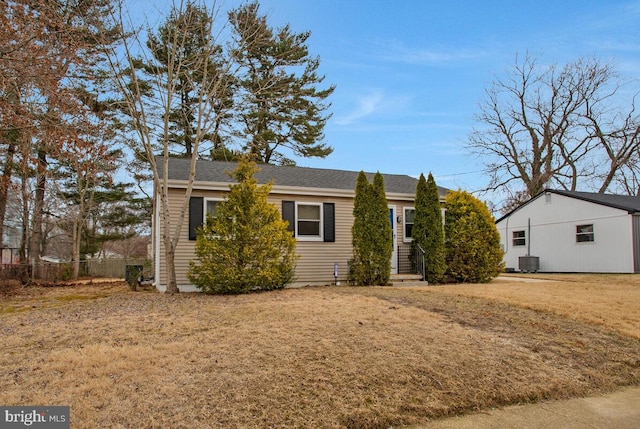 ranch-style home with central air condition unit, fence, and a front yard