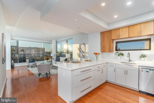 kitchen featuring white cabinetry, sink, light hardwood / wood-style flooring, stainless steel dishwasher, and kitchen peninsula