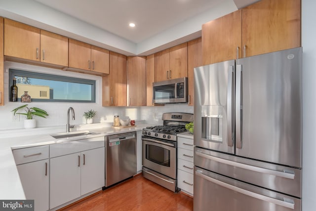 kitchen featuring appliances with stainless steel finishes, backsplash, sink, white cabinets, and light hardwood / wood-style floors