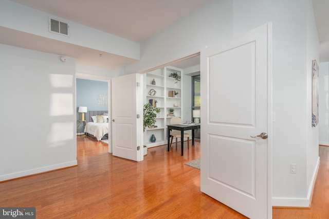 corridor with built in features and wood-type flooring