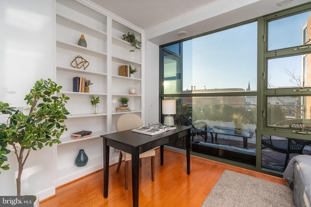 home office featuring crown molding, built in features, and light hardwood / wood-style flooring