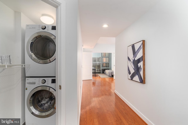 washroom featuring hardwood / wood-style floors and stacked washer / dryer