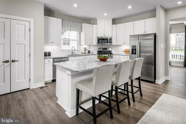 kitchen featuring sink, a kitchen island, a breakfast bar area, white cabinets, and appliances with stainless steel finishes