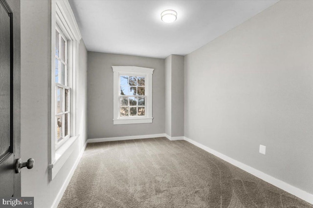 spare room featuring carpet floors and baseboards