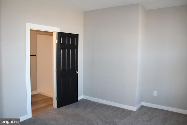 unfurnished bedroom with dark carpet and baseboards