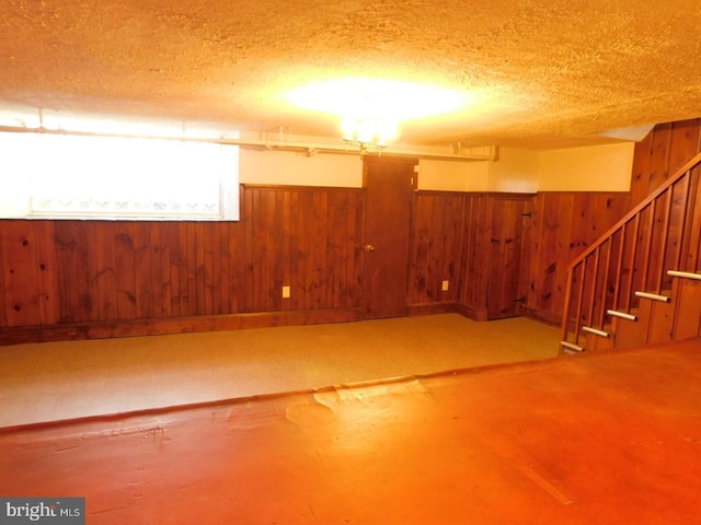 basement featuring a textured ceiling and wood walls