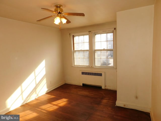 unfurnished room with dark hardwood / wood-style flooring, radiator, and ceiling fan