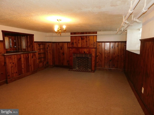 basement with a notable chandelier, a fireplace, a textured ceiling, and wood walls