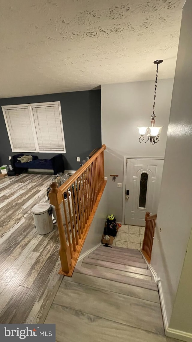 stairway featuring hardwood / wood-style flooring, a chandelier, and a textured ceiling