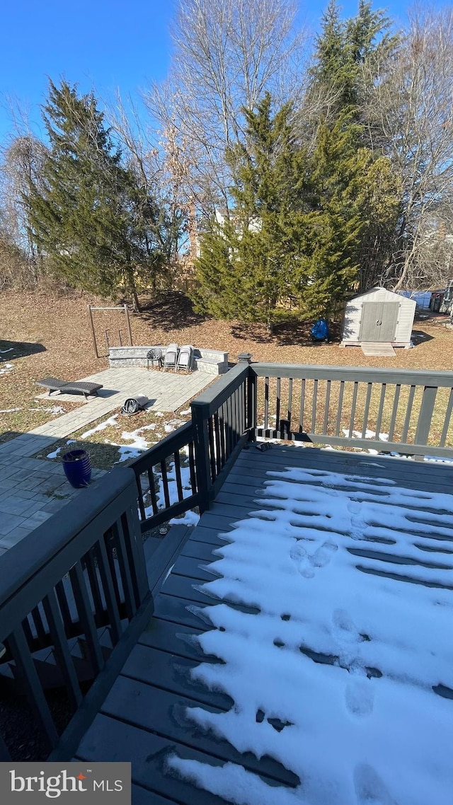 wooden deck featuring an outdoor fire pit and a shed