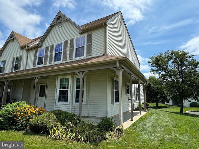 view of side of property with covered porch and a lawn