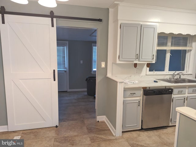 kitchen featuring a barn door, sink, and stainless steel dishwasher