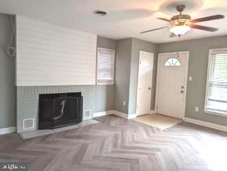 entryway with parquet flooring, a large fireplace, and ceiling fan