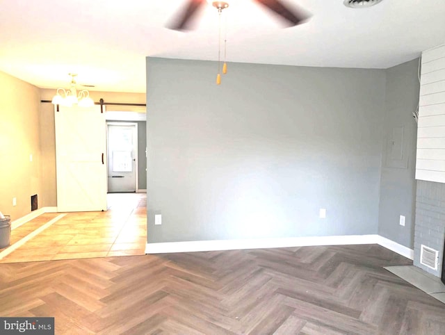 unfurnished room featuring a barn door, ceiling fan, and parquet floors