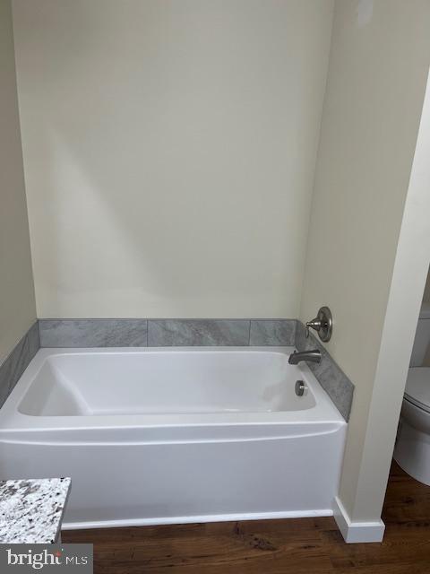 bathroom featuring vanity, hardwood / wood-style floors, a tub, and toilet