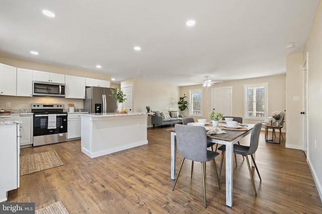 kitchen featuring a kitchen island, wood-type flooring, appliances with stainless steel finishes, and white cabinets