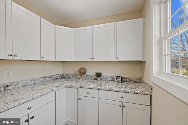 kitchen with white cabinetry and light stone counters