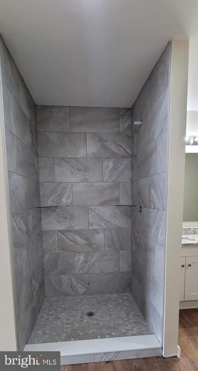 bathroom featuring vanity, hardwood / wood-style floors, and a tile shower