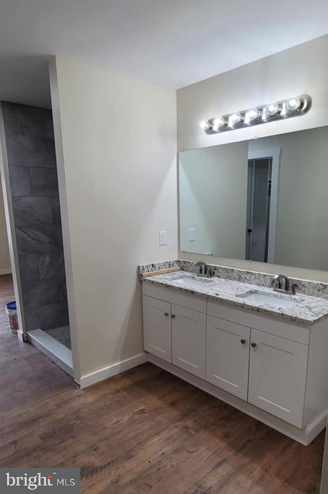 bathroom with vanity, hardwood / wood-style floors, and tiled shower