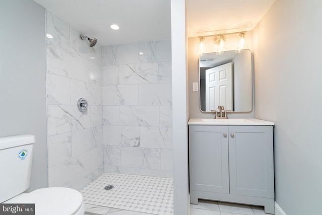 bathroom featuring vanity, toilet, and tiled shower