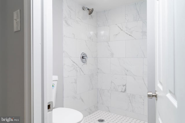 bathroom featuring tiled shower and toilet